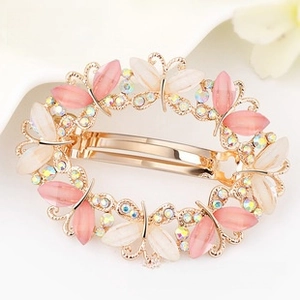 Macro detail of golden butterfly hair clip with pink opal stones and rhinestones