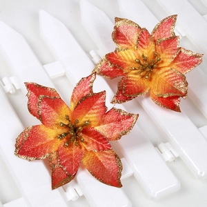 Close-up of artificial poinsettia flowers with gold glitter edges on white fence