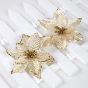 Detail showing two gold glitter poinsettia flowers with gold trim on a white fence