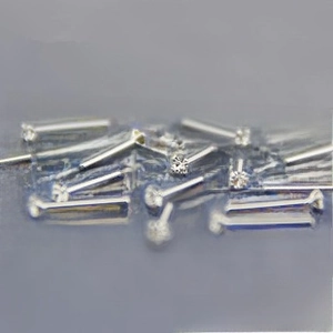 Macro shot of silver 925 studs with round clear zircon stones on a dark textured background