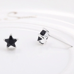 Macro view of black star-shaped zircon stud earrings with silver bezel and pin detail