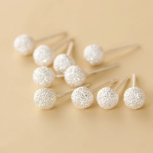 Close-up of 925 sterling silver ball earrings with textured finish and black zircon stones
