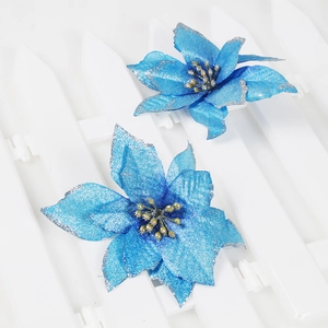 Detail of two blue Christmas poinsettia flowers with silver glitter edges on white fence