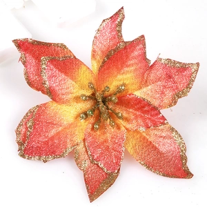 Macro view of artificial Christmas poinsettia with red-orange gradient and gold glitter edges