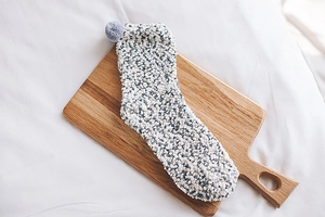 Close-up of blue and white coral fleece socks with pom-poms on a wooden board