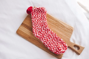 Detail of red and white striped coral fleece thermal socks with plush pom-poms on wood