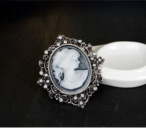 Macro detail of vintage cameo brooch with woman portrait and rhinestone floral border