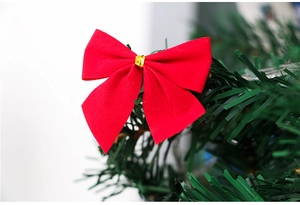 Macro view of red velvet Christmas bows with gold ties on green pine tree needles