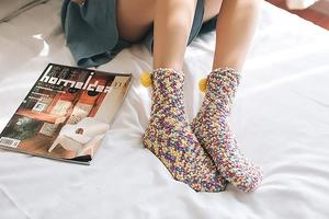 Detail of coral fleece thick socks with colorful popcorn texture and yellow pompom