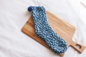 Detail of blue and white coral fleece socks with soft pom-pom on a wooden board