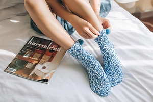 Detailed texture of blue and white coral fleece socks featuring soft ankle pom-poms