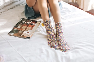 Detailed close-up of soft coral fleece socks with cute pom-pom trim in a cozy setting