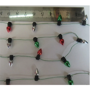 Macro shot of colorful 1cm mini Christmas bulbs next to a ruler for size scale reference