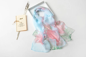 Close-up of lightweight light blue silk scarf with elegant pink lotus floral prints