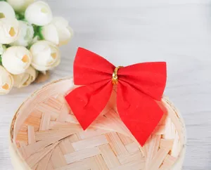 Detail shot of a 6cm red flocked Christmas bow with gold tie on a woven basket