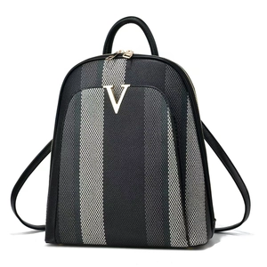 Close-up of striped canvas backpack featuring a golden V-shaped logo and black PU leather trim
