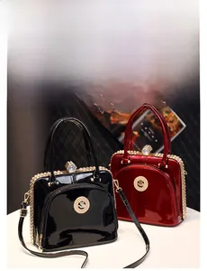 Close-up of glossy patent leather handbags with metallic logo and chain hardware detail
