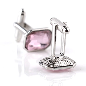 Macro view of men's silver cufflinks with rectangular pink crystals on white reflection