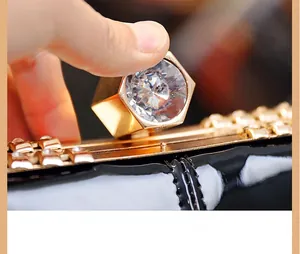Close-up of elegant black lacquer bag featuring a hexagonal crystal clasp and gold edges