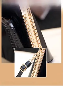 Close-up of black patent leather handbag featuring golden hardware and diamond edges