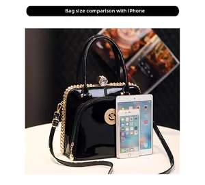 Size comparison of black patent leather handbag with phone and tablet for scale
