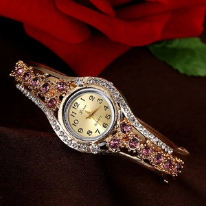 Detailed view of women's gold-toned quartz watch with purple rhinestones and hollow band
