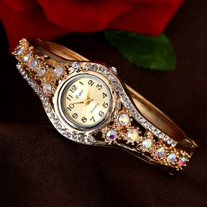 Elegant gold quartz bangle watch for women with rhinestones on brown fabric background