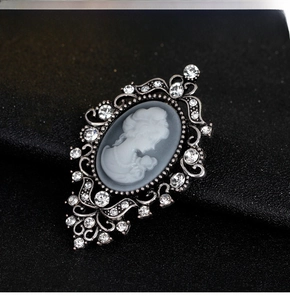 Close-up of vintage cameo brooch with white silhouette and shimmering crystal inlay