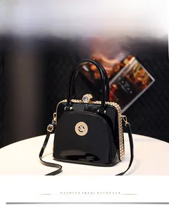 Close-up of black patent leather handbag with cat logo and rhinestone encrusted lock