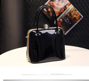Close-up of black patent leather handbag with gold hardware and crystal clasp