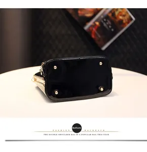 Close-up of black patent leather bag bottom with four gold protective metal studs