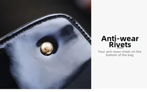 Detail view of the black patent leather handbag base with four protective gold metal rivets