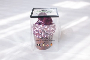Close-up of cozy purple and pink cupcake-styled coral fleece socks in a gift box