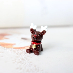 Détail d'une figurine de renne marron en résine avec clochette dorée pour Noël