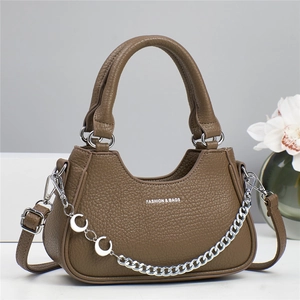 Brown lychee leather tote bag with silver chain and adjustable strap in minimalist setting