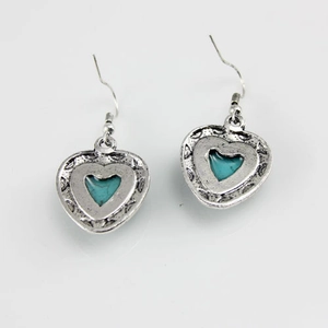Macro view of vintage heart earrings featuring antique silver finish and turquoise stones