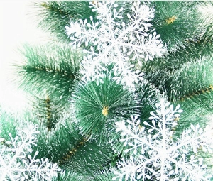 Detail of green faux pine needles with white snowflake ornaments for holiday decor