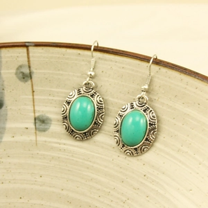 Detail of bohemian turquoise drop earrings featuring vintage silver engraved patterns