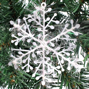 Close-up of 11cm white snowflake ornament with iridescent glitter on a Christmas tree