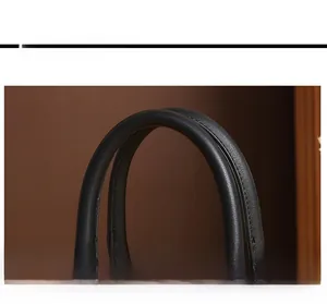 Detailed close-up of thick rounded leather handle with fine stitching on black handbag