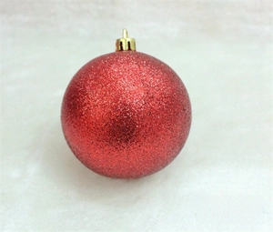 Detail of a 3cm red Christmas ball with shiny glitter finish and a gold hanging loop