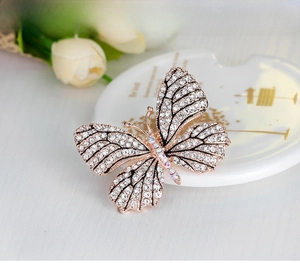 Detail of rose gold butterfly brooch with shimmering rhinestones on white tray