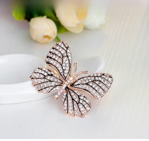 Close-up of rose gold butterfly brooch with shimmering crystals on a floral background
