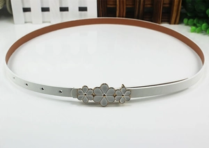 Close-up of white women's skinny belt featuring a floral gold buckle with enamel petals