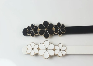 Detail of thin PU leather belts with golden floral buckles in black and white colors