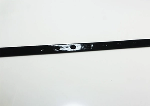 Close-up of black patent leather belt holes with a glossy finish for women