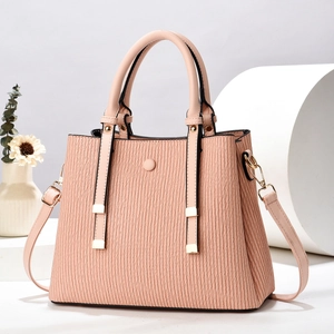 Detail of pink pleated tote bag with golden hardware and detachable strap on white stand
