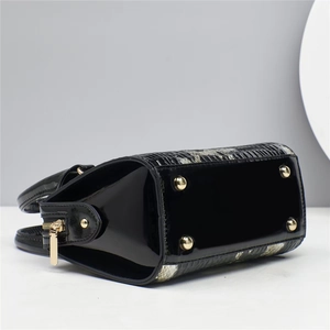 Detail view of large handbag with gold metal feet and premium black patent leather base