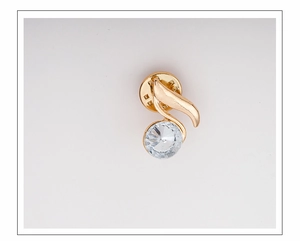 Macro detail of a gold leaf brooch with a clear faceted crystal on a white background