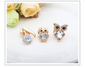 Detailed view of three golden owl brooches with rhinestones on a white ceramic plate